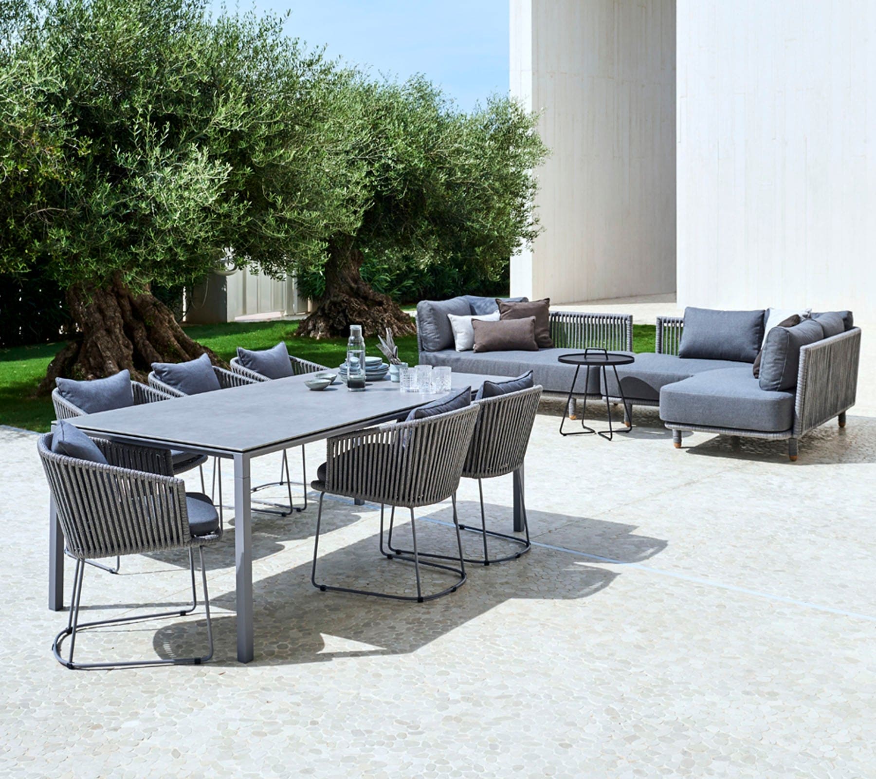 Boxhill's Moments Outdoor Dining Armchair lifestyle image with dining table and Moments Module Sofa at patio