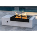 Black and white rectangular outdoor metal powdered coated fire pit table with flame set on a tiled surface beside the pool