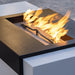 Close up view of a black and white rectangular metal powdered coated fire pit table with flames emerging from the burner