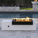 Black and white rectangular outdoor metal powdered coated fire pit table with flame set on a tiled surface beside the pool