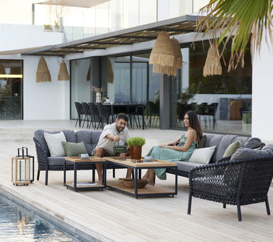 Boxhill's Ocean Large Outdoor Lounge Chair lifestyle image beside the pool with other Ocean Sofa Collection, Level Coffee Table with Teak Top and 2 people sitting down