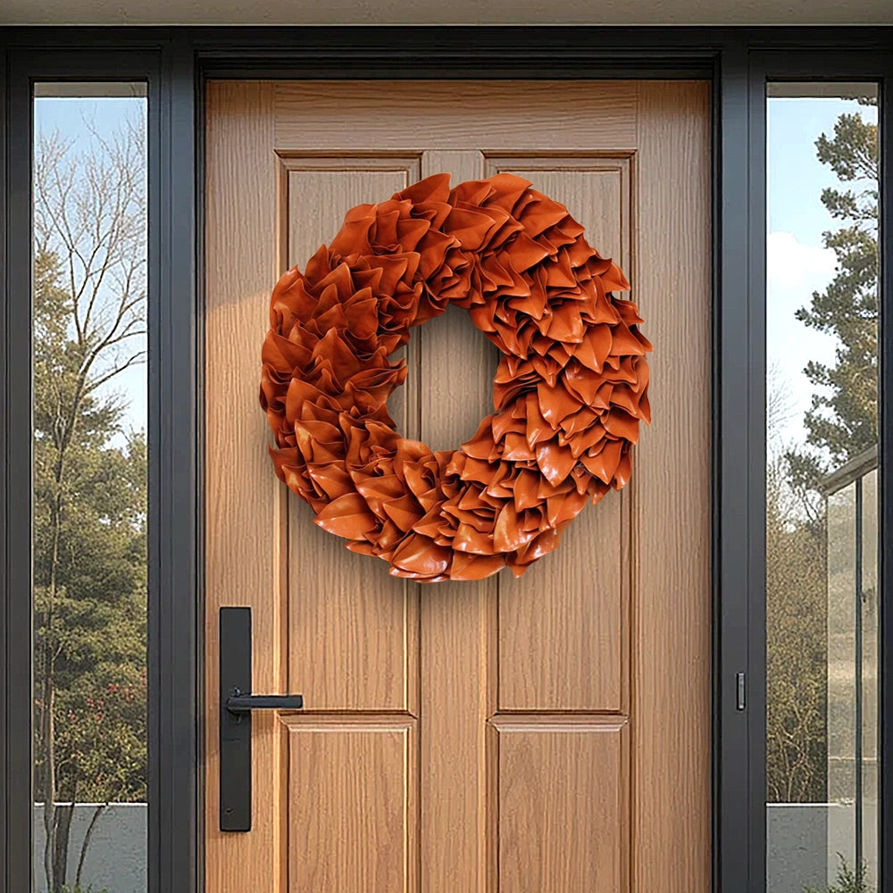 Orange lacquer wreath hanging on a light brown wooden front door with black frame and glass side panels.