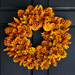 Orange pinecone wreath on a black door