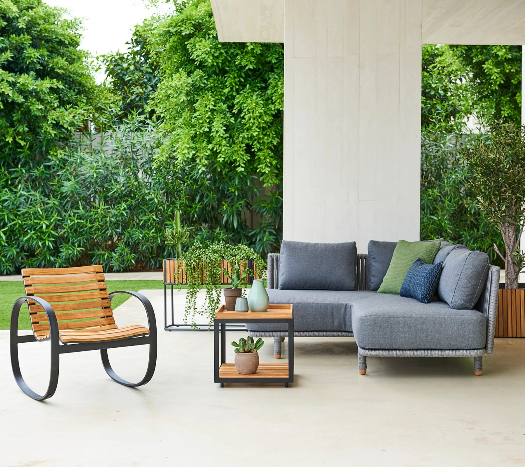 Boxhill's Parc teak outdoor rocking with teak square table and grey outdoor sectional sofa placed in patio