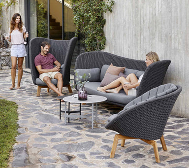  Boxhill's Peacock dark grey outdoor wing 3-seater sofa with a woman sitting on it having a chat to man sitting on the other chair