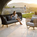 Boxhill's Peacock dark grey outdoor wing 3-seater sofa with a woman sitting on it and Nest weave outdoor lounge chair 