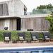 Boxhill's Peacock dark grey outdoor wing highback chair with small dark grey round table in a row placed beside the pool