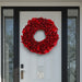 Decorative red lacquer wreath on a modern front door with black frame and glass side panels.