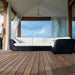 Boxhill's Savannah black outdoor sectional sofa with white cushion placed on wooden patio with a man leaning on pillar