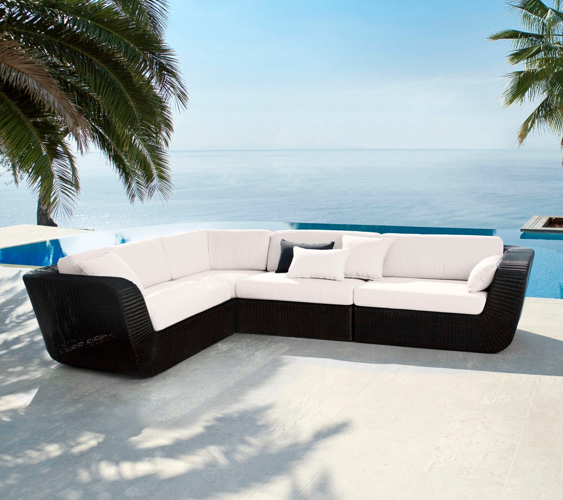 Boxhill's Savannah black outdoor sectional sofa with white cushion placed beside the pool with palm trees