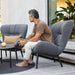  Boxhill's Serene grey outdoor lounge chair placed on wooden patio with a man sitting on it and grey outdoor round table