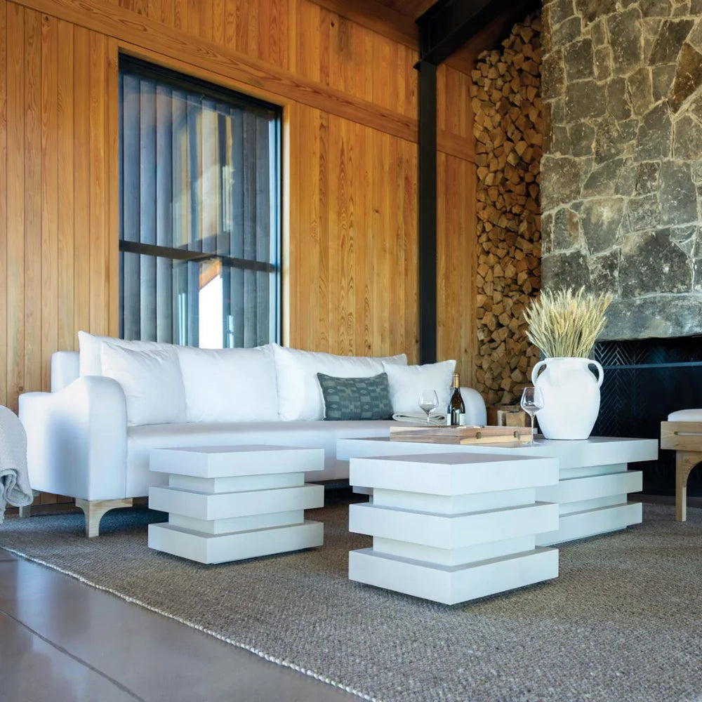 Modern outdoor living space with white furniture and a stone wall.