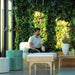 Man sitting on a white outdoor lounge chair in a modern indoor setting with greenery and plants.