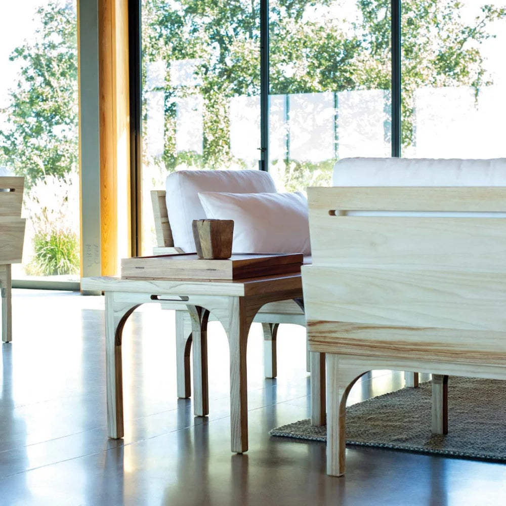 Modern living room with white sofa, wooden outdoor  side table, and large windows.