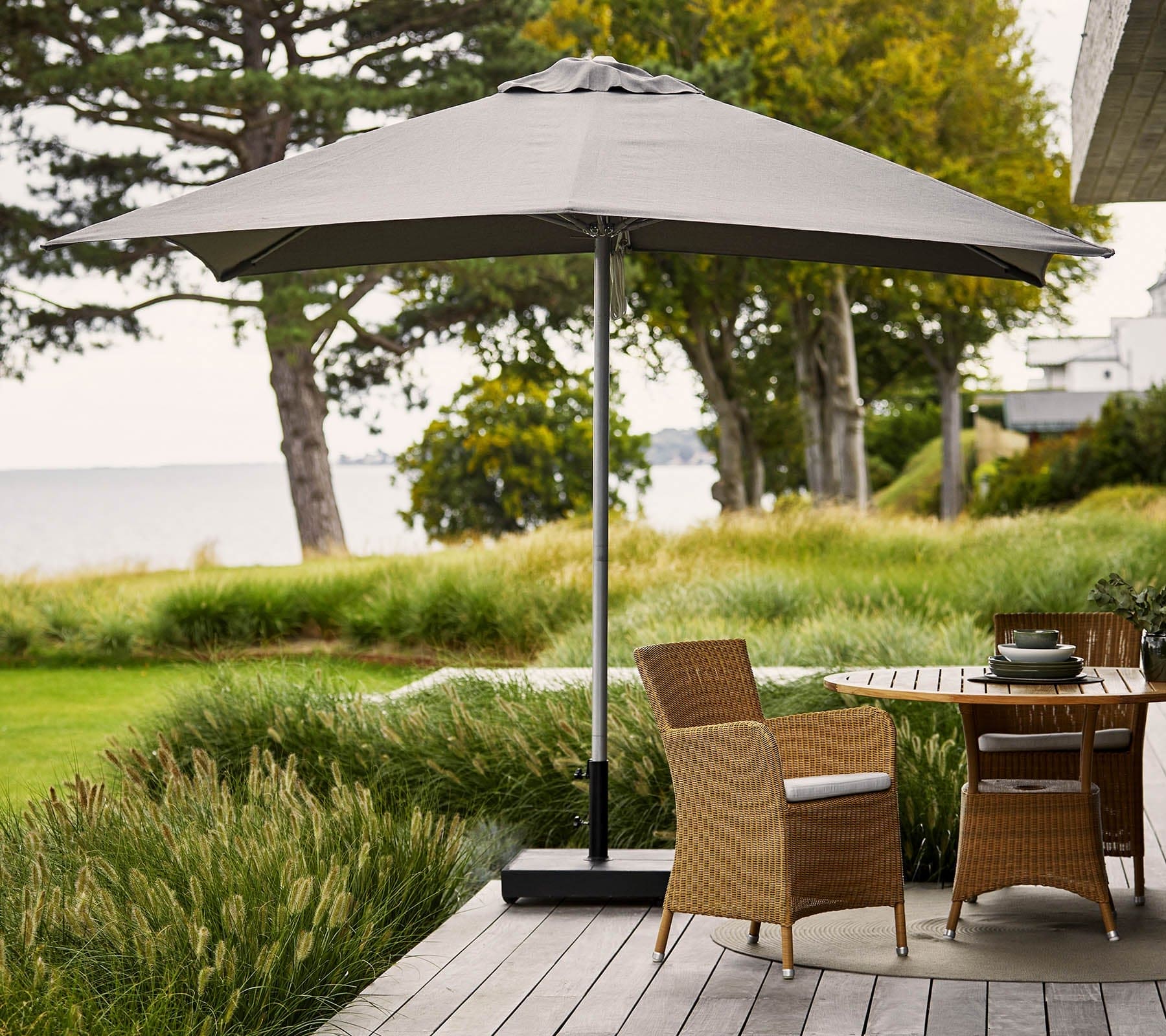 Boxhill's Shadow light grey parasol with pulley system | 3x3 m on wooden platform with teak round table and 2 brown chair