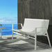 Modern white aluminum outdoor bench on a patio against a concrete wall, with a sea view