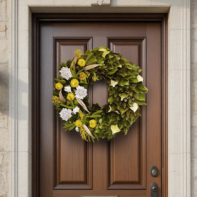 Decorative wreath made of natural and magnolia leaves in yellow-green hues, mounted on a brown wooden front door.