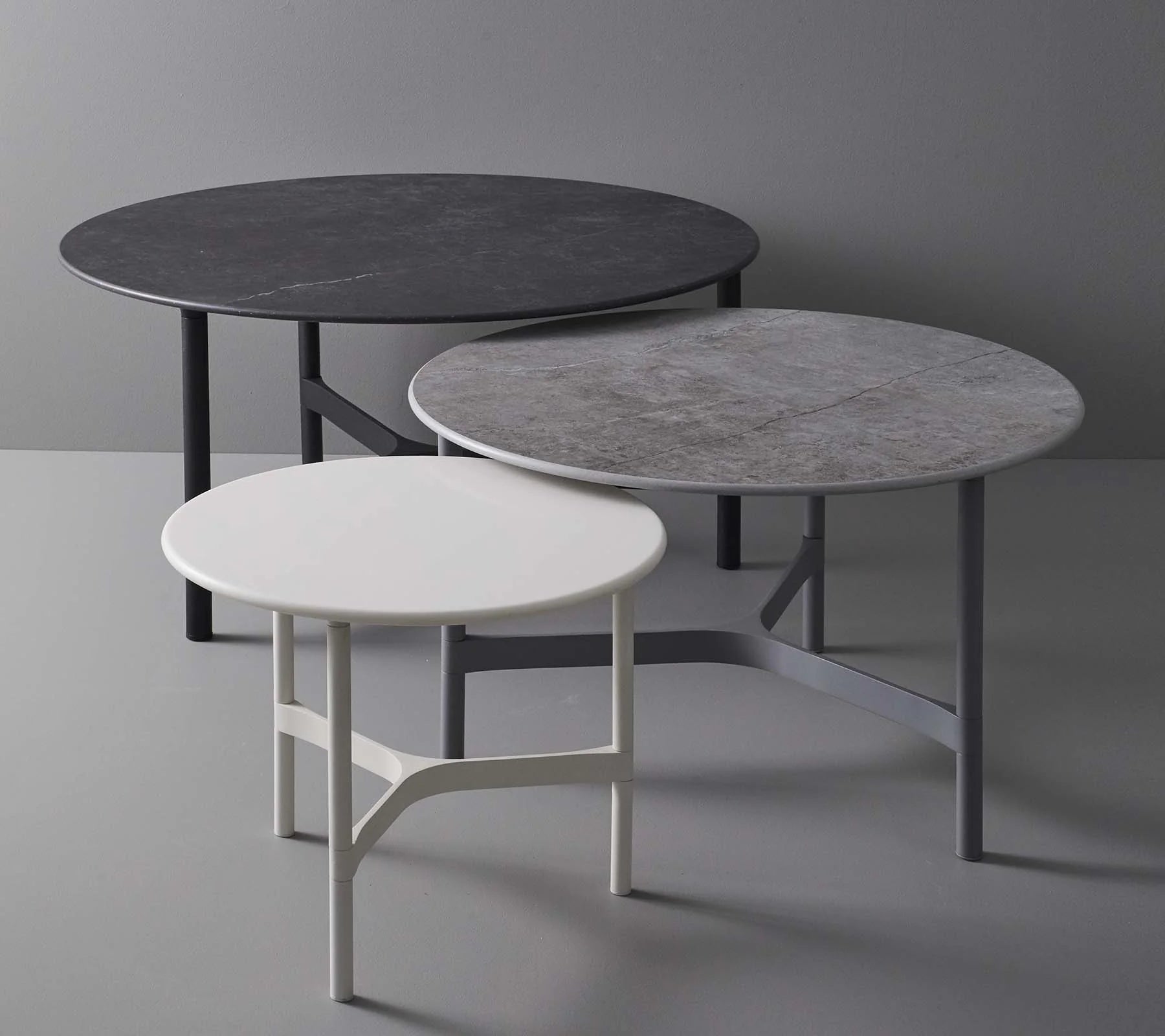  Boxhill's Twist outdoor round coffee table in black, grey and white colors with different sizes placed against grey wall