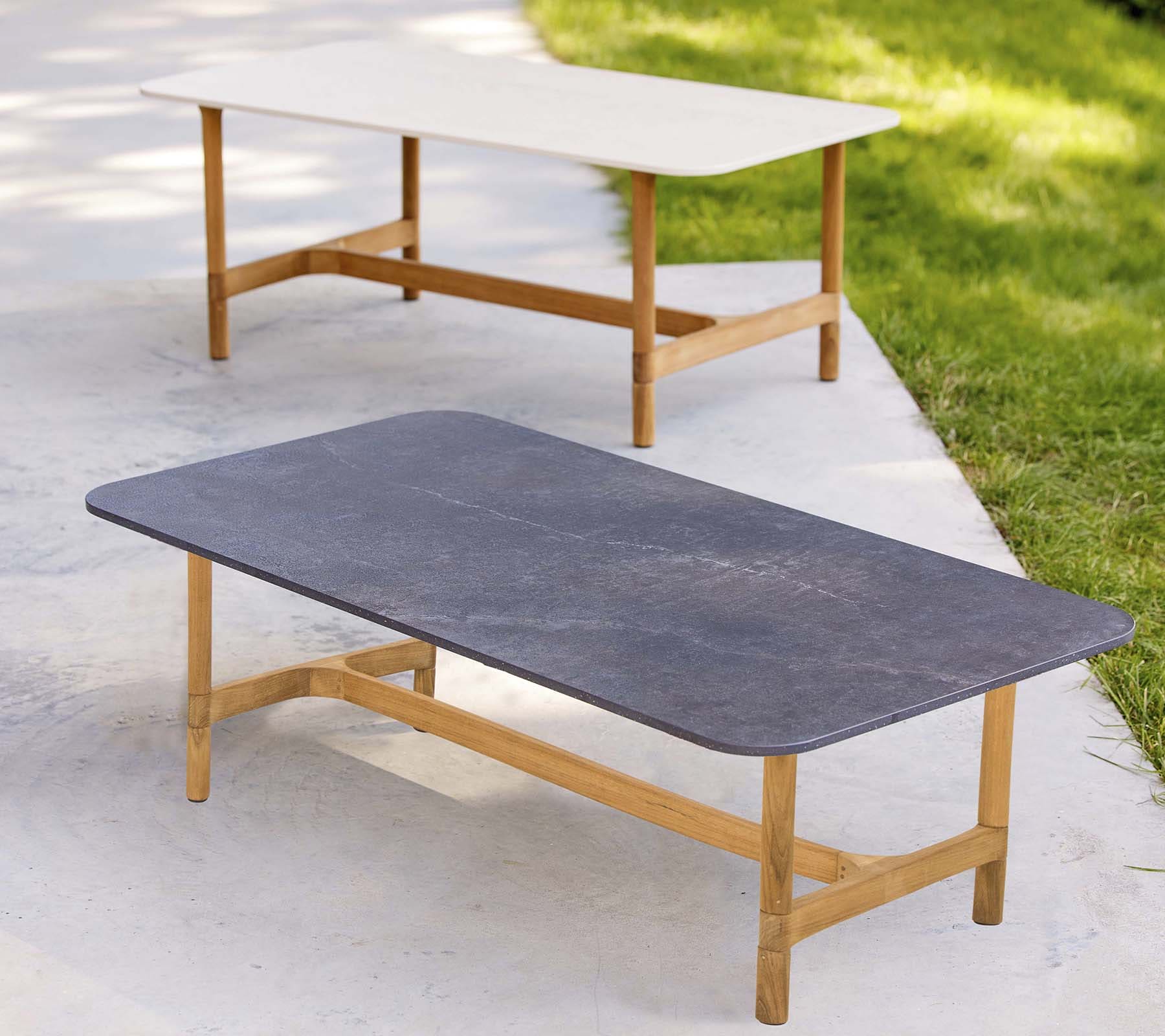 Boxhill's Twist dark grey and white rectangular outdoor coffee table with teak frame placed on white cement floor