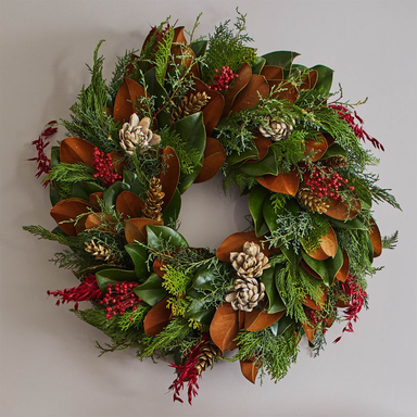 Decorative wreath with greenery, brown leaves, and red berries on a plain background