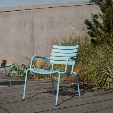 Light blue aluminum outdoor lounge chair on wooden deck patio with grass behind it