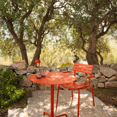 A vibrant outdoor red table with a single red outdoor chair, creating a bold and inviting seating area.