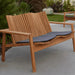 A natural teak outdoor two-seater sofa with slatted back, woven trim, and dark gray seat cushions.