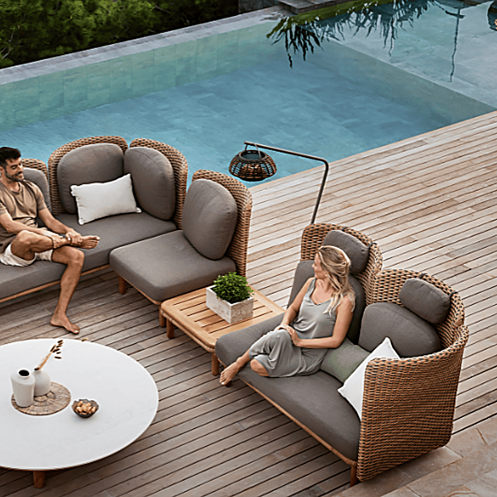 Boxhill's Arch Outdoor Neck Cushion lifestyle image attach on Arch 2 Seater Sofa with man and woman sitting down beside the pool