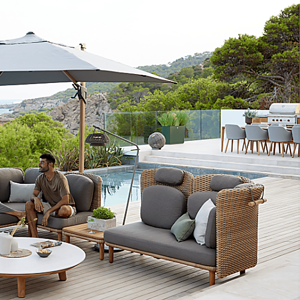 Boxhill's Arch Outdoor Neck Cushion lifestyle image attach on Arch 2 Seater Sofa with man sitting down beside the pool