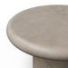 Close-up of a round concrete stool or table top in a warm light gray-beige tone, showing the textured surface and curved rim against a plain white background.