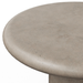 Close-up of a round concrete table top in a warm light gray-beige tone, showing the textured surface and curved edge against a plain white background.