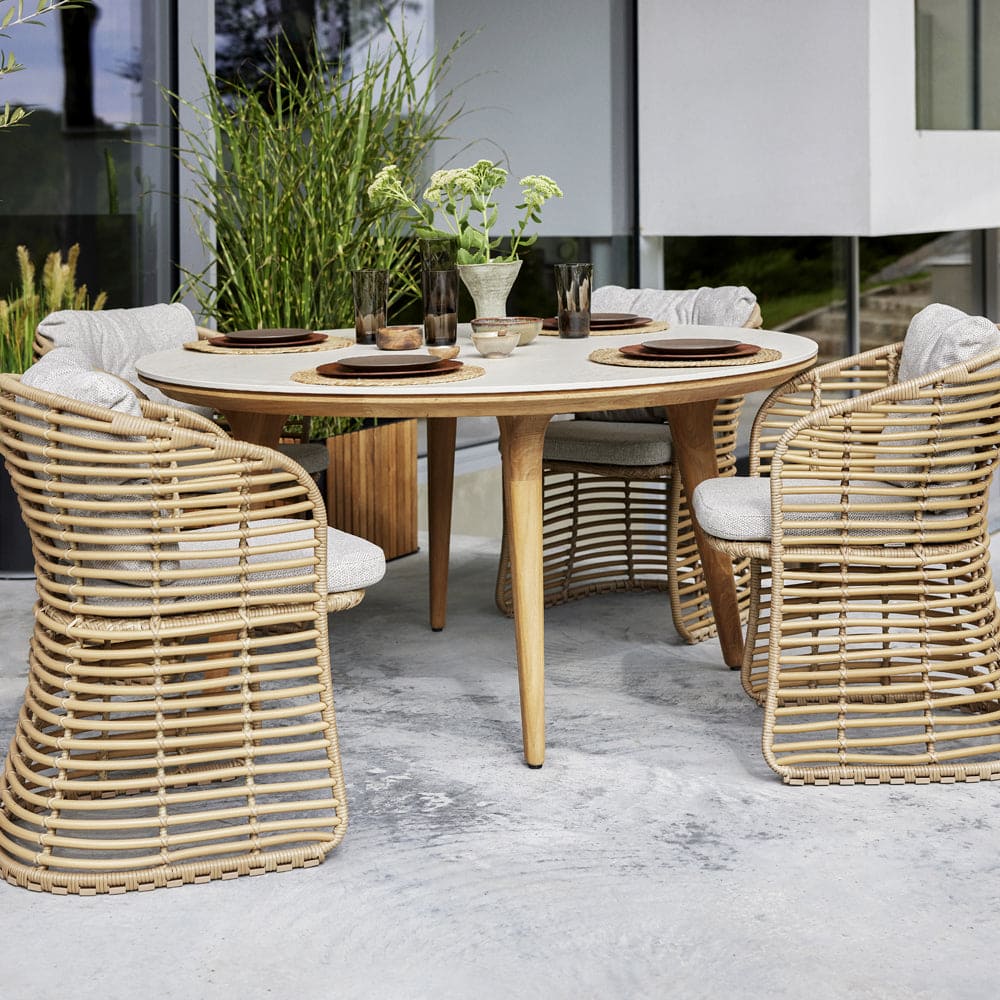 Boxhill's Aspect Teak Round Dining Table Travertine Look lifestyle image with dining chairs around and plates and glass of water on top