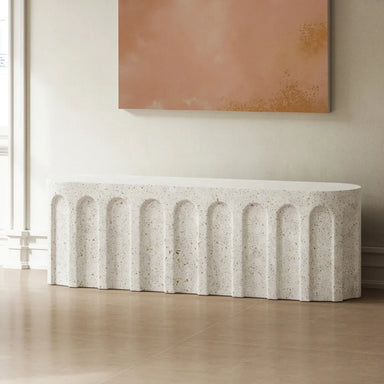 Speckled white concrete oval bench in a modern interior against a beige wall with brown abstract painting