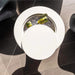 A modern round white side table with a circular ice bucket insert filled with ice and two green beverage cans, photographed from above on dark gray tiled flooring.