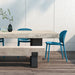 Two blue armless outdoor side chairs beside a rectangular concrete table and bench on a wooden deck patio