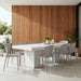 Patio dining with white rectangular concrete table and eight gray outdoor dining chairs in front of wood slat wall