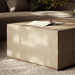 Close-view of  beige rectangular concrete outdoor coffee table on a textured rug in front of a sofa