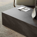 Dark gray textured rectangular concrete outdoor coffee table with magazine and vase on top, placed on a gray rug