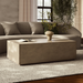 Beige textured rectangular concrete outdoor coffee table on a gray rug in front of a beige sofa in a modern living room