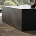 Close-view of a dark gray concrete square coffee table on top of a textured rug
