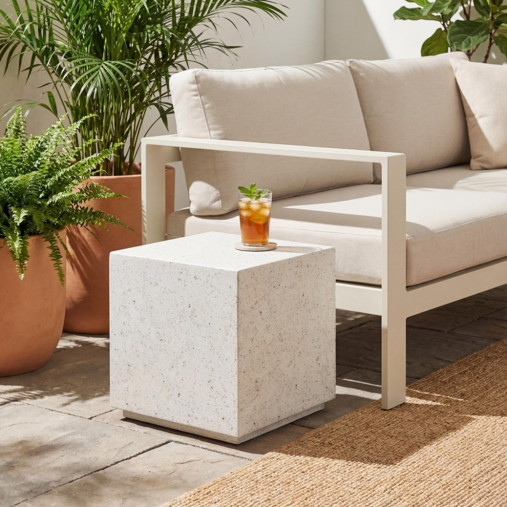 Modern patio with square white speckled outdoor side table beside a light beige sofa and two planters with plants