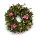 Decorative green leaf wreath with soft pink, purple, and white flowers against a white background.