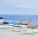 Outdoor furniture set with chairs and a table on a deck overlooking the ocean.