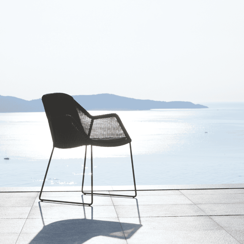 Boxhill's Breeze Dining Weave Chair Black lifestyle at the seafront back side view
