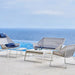 Outdoor furniture set with chairs and a table on a deck overlooking the ocean.