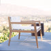 Wooden outdoor chair with white batyline on a balcony with a blurred outdoor background