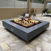 A gray outdoor square powdered coated fire pit with a vibrant flame placed on a tiled surface modern outdoor patio