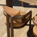 Close-up view of brown modern outdoor armchairs on a wooden deck beside dining table