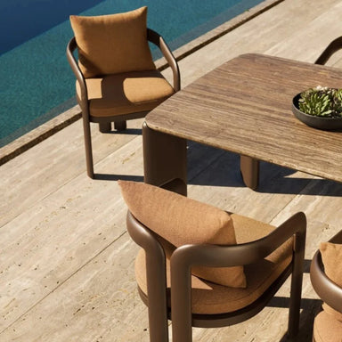 Rectangular patio dining table with a textured surface, accompanied by two brown dining chairs, placed beside the pool