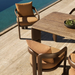 Modern outdoor dining chairs with brown cushions and a texture dining table placed beside the pool